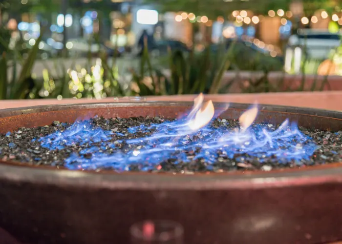 A closeup view of a firepit with rocks in it and a blue flame